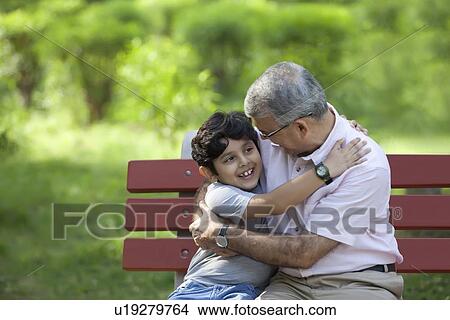 Picture - Grandfather and grandson hugging in a park. Fotosearch