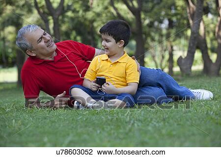 Grandfather and grandson listening to music in a park View Large Photo Image Stock Image - Grandfather and grandson listening to music in a park. Fotosearch