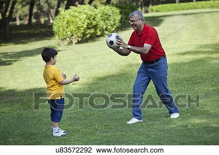 Stock Image - Grandfather and grandson playing in a park. Fotosearch