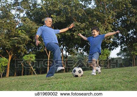 Stock Image - Grandfather and grandson playing soccer. Fotosearch