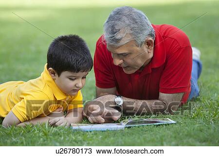 Grandfather and grandson reading a book in a park View Large Photo Image Stock Image - Grandfather and grandson reading a book in a park. Fotosearch