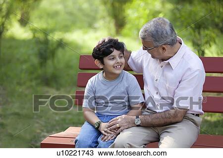 Grandfather and grandson sitting in a park View Large Photo Image Stock Image - Grandfather and grandson sitting in a park. Fotosearch