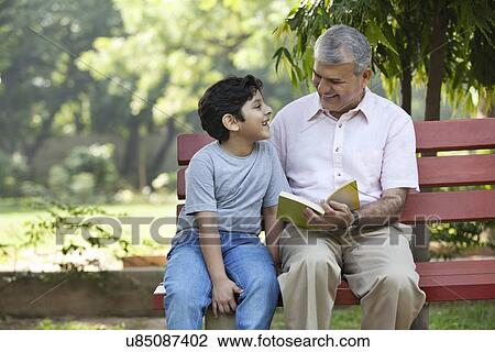 Stock Image - Grandfather and grandson sitting in a park. Fotosearch