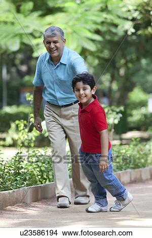 Grandfather and grandson taking a walk in a park View Large Photo Image Picture - Grandfather and grandson taking a walk in a park. Fotosearch