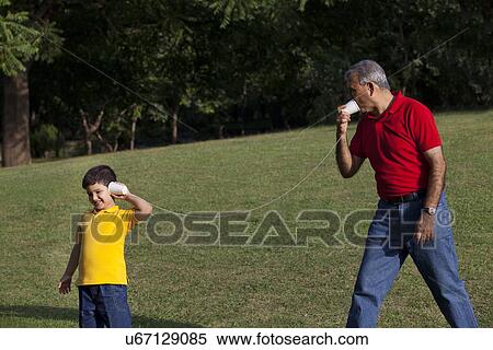 Stock Photography - Grandfather and grandson talking through paper cups. Fotosearch