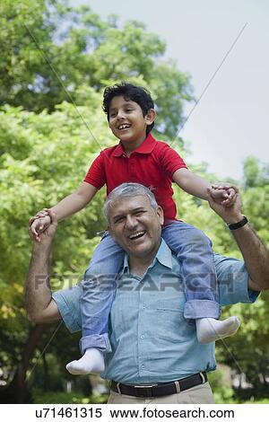 Stock Photography - Grandfather carrying his grandson on his shoulders. Fotosearch