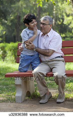 Grandfather smiling after listening to grandsons secret View Large Photo Image Stock Photo - Grandfather smiling after listening to grandsons secret. Fotosearch