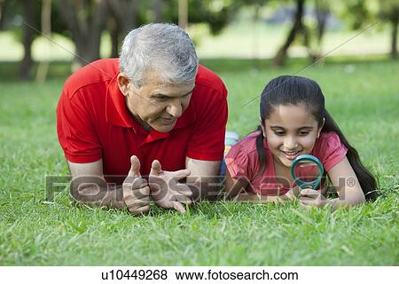 Grandfather teaching his granddaughter to use magnifying glass View Large Photo Image Stock Photo - Grandfather teaching his granddaughter to use magnifying glass. Fotosearch