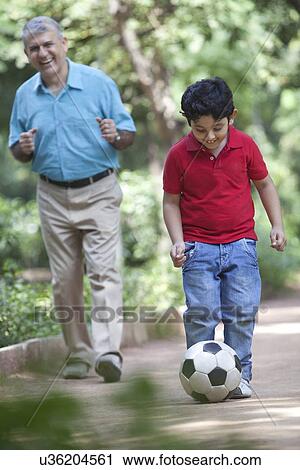 Grandson playing soccer as grandfather watches on View Large Photo Image Stock Image - Grandson playing soccer as grandfather watches on. Fotosearch