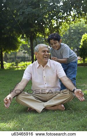 Stock Photograph - Grandson tickling grandfather in ear. Fotosearch