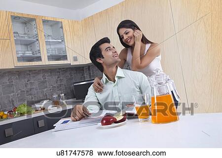 Stock Photo - Happy couple with catalogues in kitchen. Fotosearch
