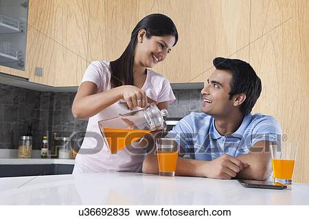 Happy woman pouring juice for man in kitchen View Large Photo Image Stock Photography - Happy woman pouring juice for man in kitchen. Fotosearch