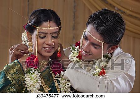 Stock Photo - Happy young bride and groom performing marriage traditions . Fotosearch