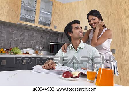 Happy young couple looking at each other in kitchen View Large Photo Image Stock Photo - Happy young couple looking at each other in kitchen. Fotosearch