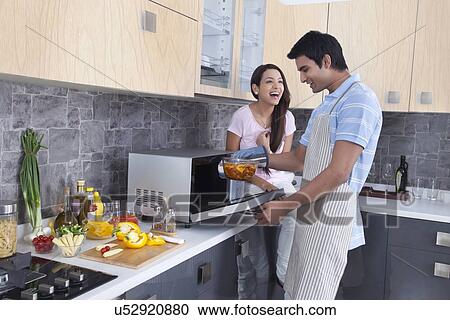 Happy young couple preparing food in kitchen View Large Photo Image Stock Image - Happy young couple preparing food in kitchen. Fotosearch
