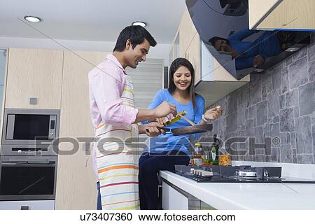 Happy young couple preparing food together in kitchen View Large Photo Image Stock Image - Happy young couple preparing food together in kitchen. Fotosearch