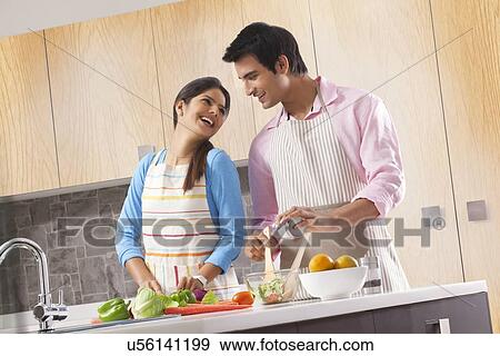 Happy young couple preparing fresh salad in kitchen View Large Photo Image Stock Photo - Happy young couple preparing fresh salad in kitchen. Fotosearch