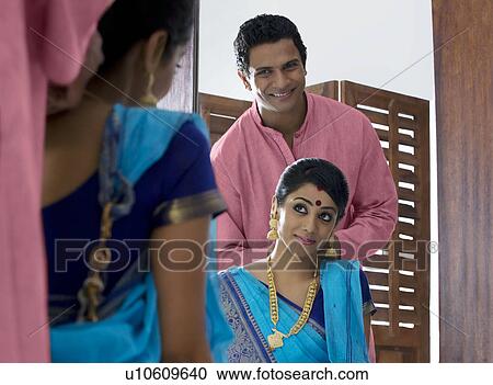 Stock Image - Husband tying a necklace around his wifes neck . Fotosearch