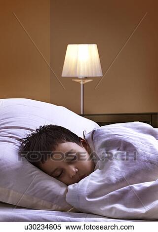 Innocent boy sleeping on bed wrapped in a blanket View Large Photo Image Stock Photography - Innocent boy sleeping on bed wrapped in a blanket . Fotosearch