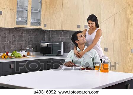 Loving woman embracing man from behind in kitchen View Large Photo Image Stock Image - Loving woman embracing man from behind in kitchen. Fotosearch