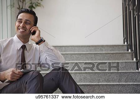 Male executive with tablet talking on a mobile phone View Large Photo Image Stock Photo - Male executive with tablet talking on a mobile phone. Fotosearch