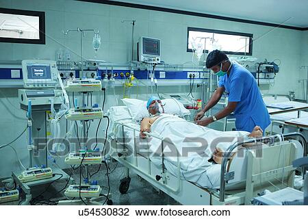 Stock Image - Male nurse with a patient in the intensive care unit . Fotosearch