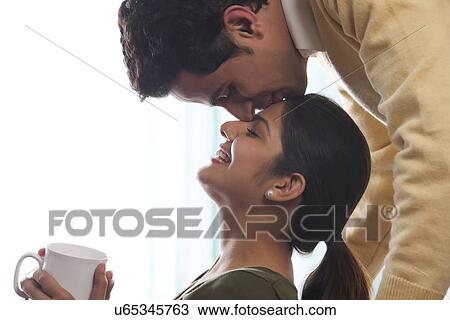 Stock Image - Man kissing a woman on her forehead. Fotosearch