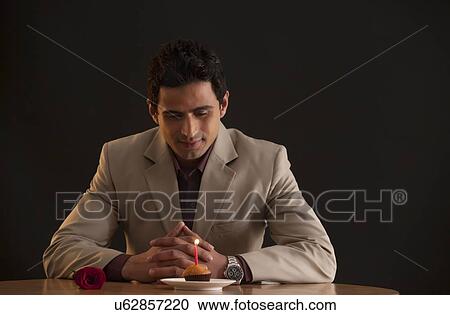 Man looking at a muffin with a candle View Large Photo Image Stock Image - Man looking at a muffin with a candle. Fotosearch