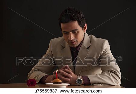 Man looking at a muffin with a candle View Large Photo Image Stock Photo - Man looking at a muffin with a candle. Fotosearch