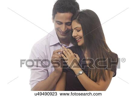 Stock Image - Man putting ring on womans finger. Fotosearch
