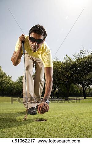 Stock Photo - Man reaching for the golf ball . Fotosearch