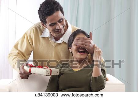 Man surprising a woman with a gift on Valentines Day View Large Photo Image Stock Image - Man surprising a woman with a gift on Valentines Day. Fotosearch