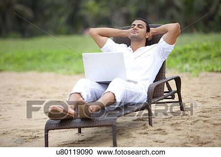 Stock Image - Man taking a nap at a beach . Fotosearch
