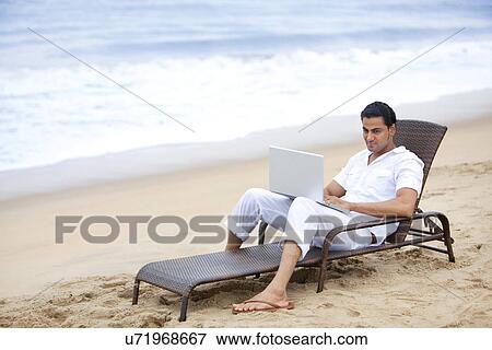 Stock Photo - Man with a laptop at a beach . Fotosearch