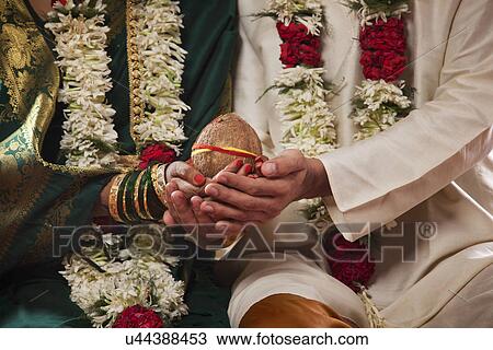 Mid section of bride and groom holding coconut together View Large Photo Image Stock Image - Mid section of bride and groom holding coconut together . Fotosearch