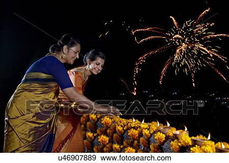 Stock Photo - Mother and daughter arranging diyas on a balcony . Fotosearch