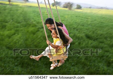 Stock Photo - Mother and daughter having fun on a swing . Fotosearch