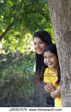 Mother and daughter hiding behind a tree View Large Photo Image Stock Image - Mother and daughter hiding behind a tree . Fotosearch