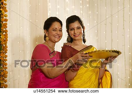 Mother and daughter holding a tray of diyas View Large Photo Image Picture - Mother and daughter holding a tray of diyas . Fotosearch