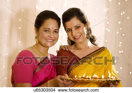 Picture - Mother and daughter holding a tray of diyas . Fotosearch