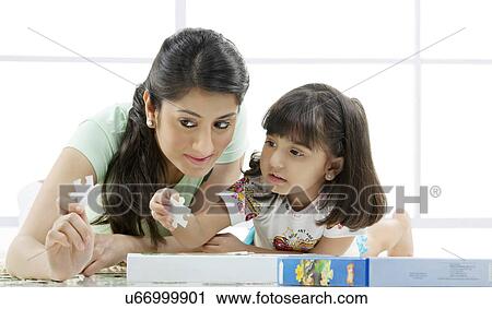 Mother and daughter holding pieces of a puzzle View Large Photo Image Stock Image - Mother and daughter holding pieces of a puzzle . Fotosearch