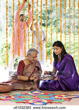Stock Image - Mother and daughter making a rangoli . Fotosearch