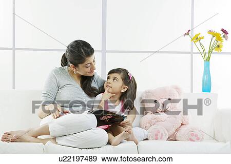 Stock Photo - Mother and daughter sitting with a magazine . Fotosearch