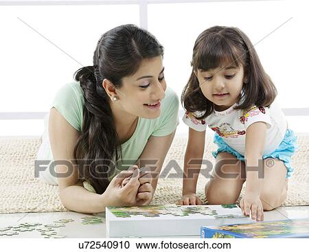 Stock Image - Mother and daughter solving a puzzle . Fotosearch