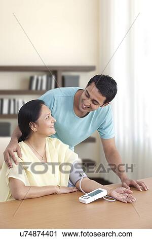 Mother and son looking at each other while measuring blood pressure View Large Photo Image Stock Image - Mother and son looking at each other while measuring blood pressure . Fotosearch