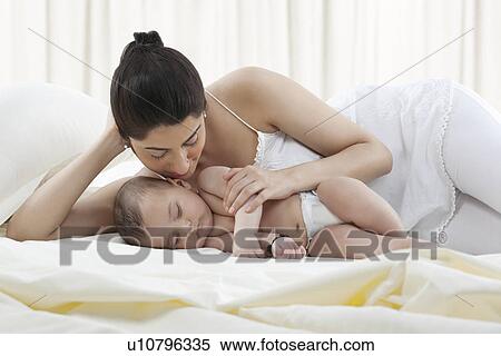 Stock Photography - Mother looking at her baby sleep . Fotosearch