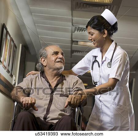 Stock Image - Nurse helping a patient on a wheelchair . Fotosearch