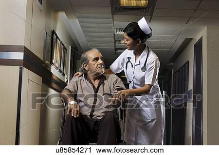 Stock Image - Nurse helping a patient on a wheelchair . Fotosearch