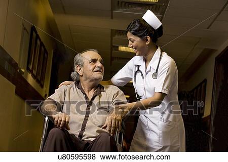 Nurse helping a patient on a wheelchair View Large Photo Image Stock Photo - Nurse helping a patient on a wheelchair . Fotosearch