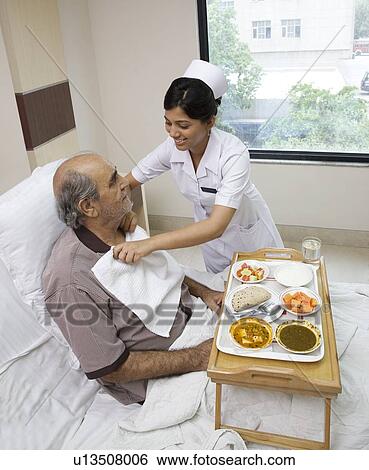 Nurse placing a napkin under a patients neck View Large Photo Image Stock Photograph - Nurse placing a napkin under a patients neck . Fotosearch